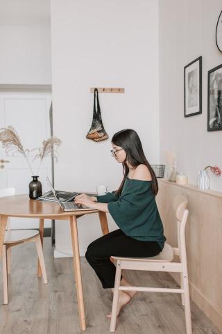 woman sat at dining table at home working on a laptop