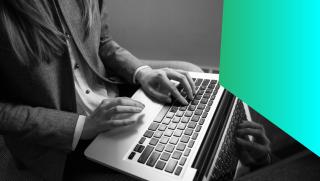 Black and white image of a female IT professional working on a laptop.